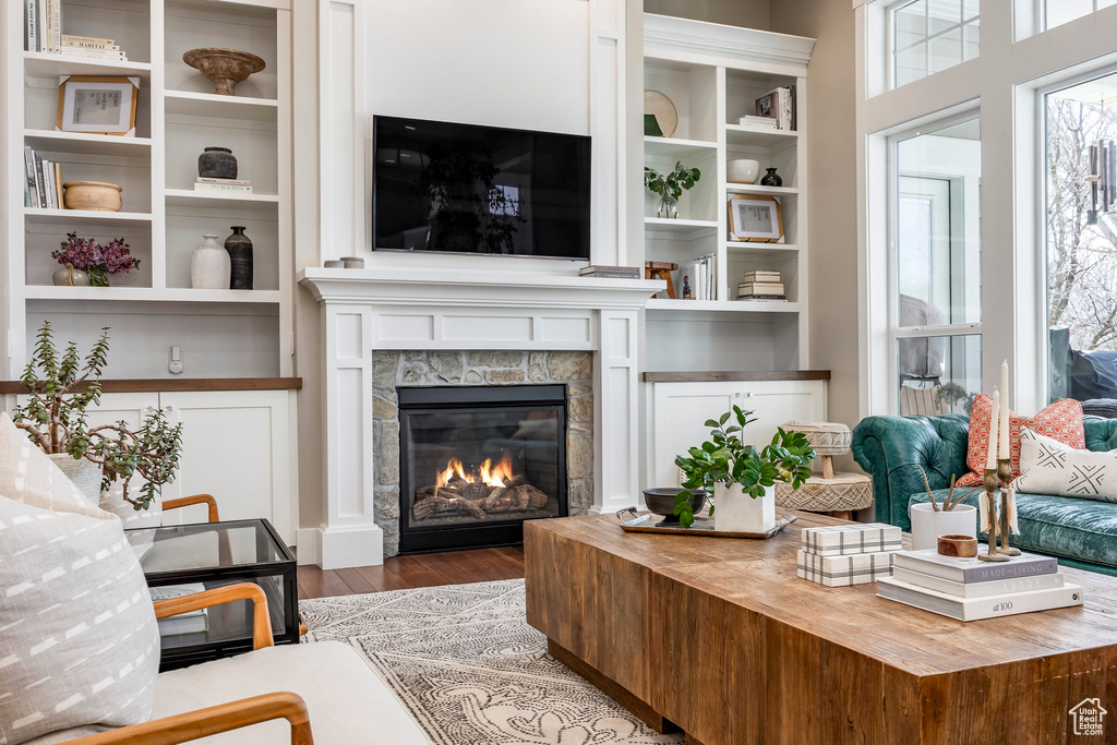 Living room with wood finished floors and a glass covered fireplace