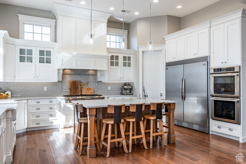 Kitchen featuring stainless steel appliances, light countertops, white cabinets, glass insert cabinets, and recessed lighting