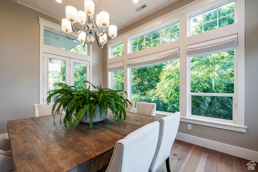 Dining space with baseboards, a chandelier, hardwood / wood-style floors, and crown molding