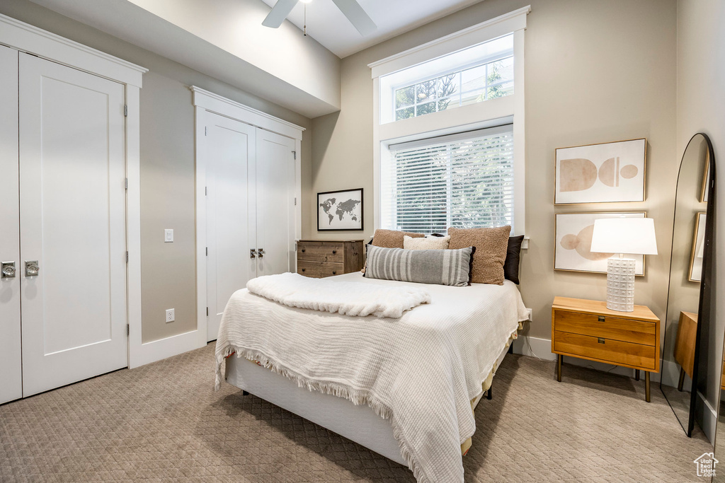Bedroom with light colored carpet, baseboards, and ceiling fan