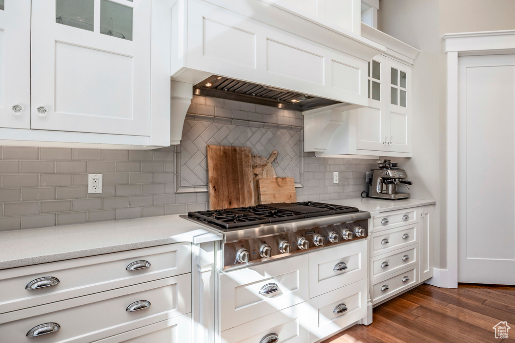 Kitchen featuring stainless steel gas cooktop, glass insert cabinets, white cabinetry, tasteful backsplash, and dark wood-style flooring