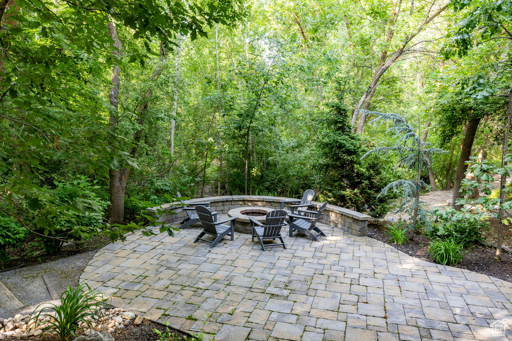 View of patio with a fire pit and a wooded view