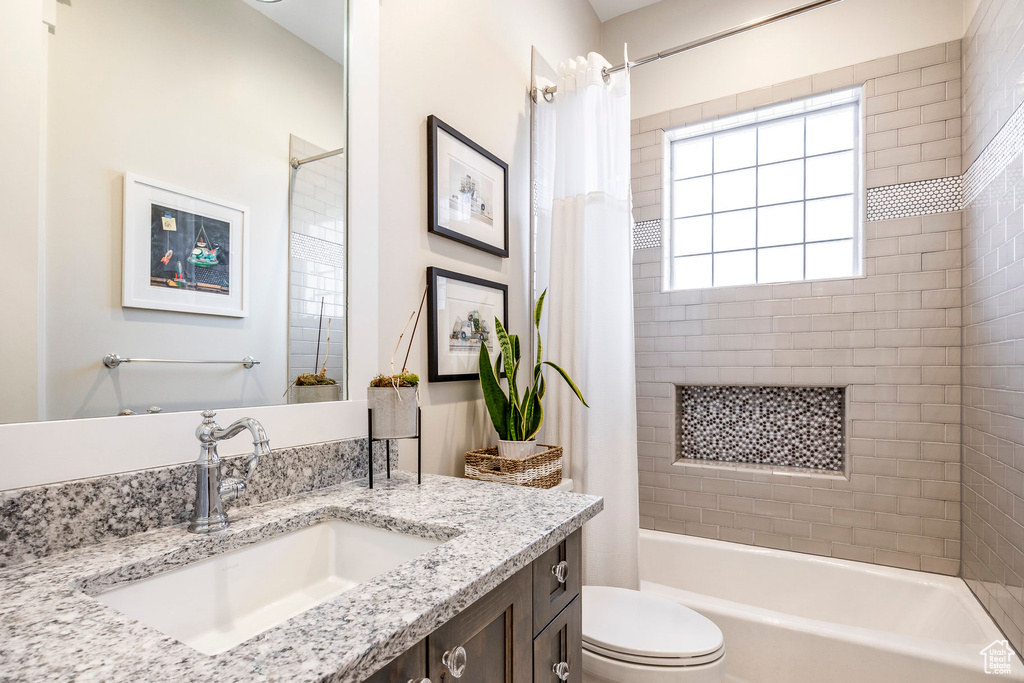 Bathroom featuring vanity, shower / bath combo with shower curtain, and toilet