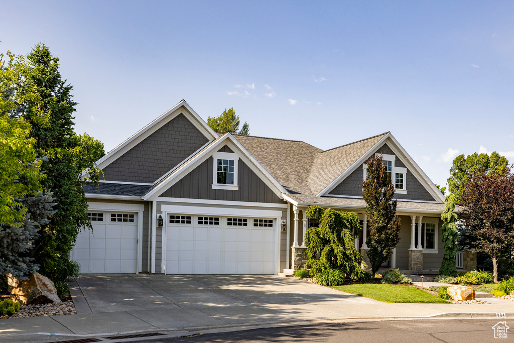 Craftsman inspired home featuring concrete driveway, an attached garage, roof with shingles, and board and batten siding