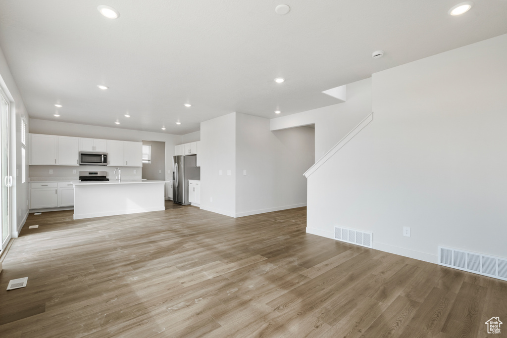 Unfurnished living room featuring visible vents, light wood-style flooring, and recessed lighting