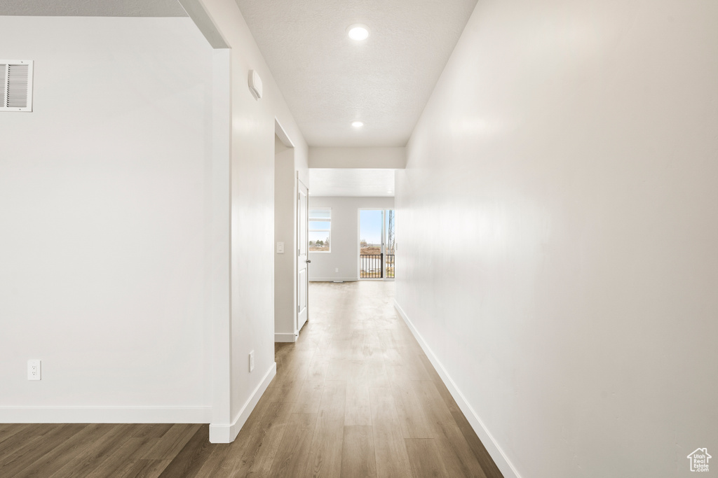 Hallway with baseboards, visible vents, wood finished floors, and recessed lighting
