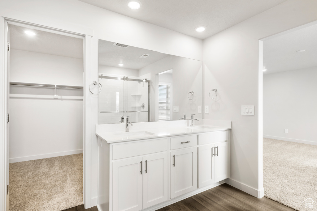 Full bathroom featuring a spacious closet, baseboards, a shower stall, a sink, and double vanity