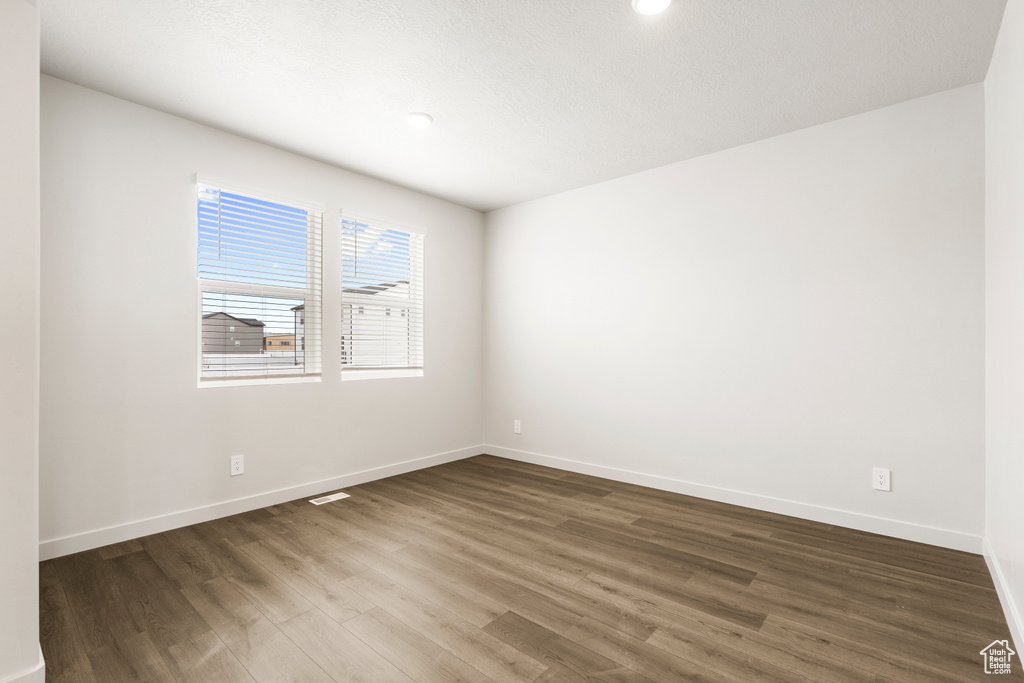 Spare room featuring baseboards, visible vents, and dark wood finished floors