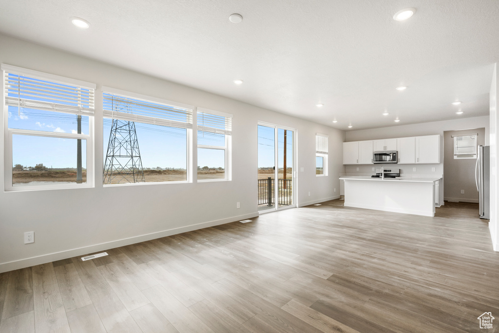 Unfurnished living room featuring baseboards, recessed lighting, and light wood-type flooring