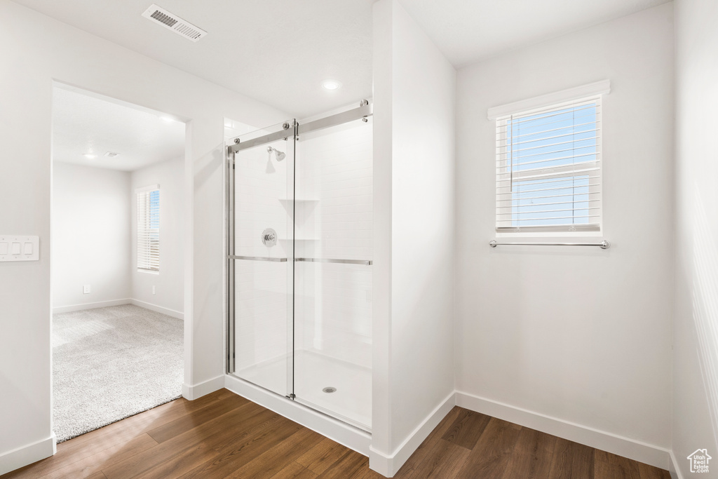 Bathroom featuring a stall shower, baseboards, visible vents, and wood finished floors