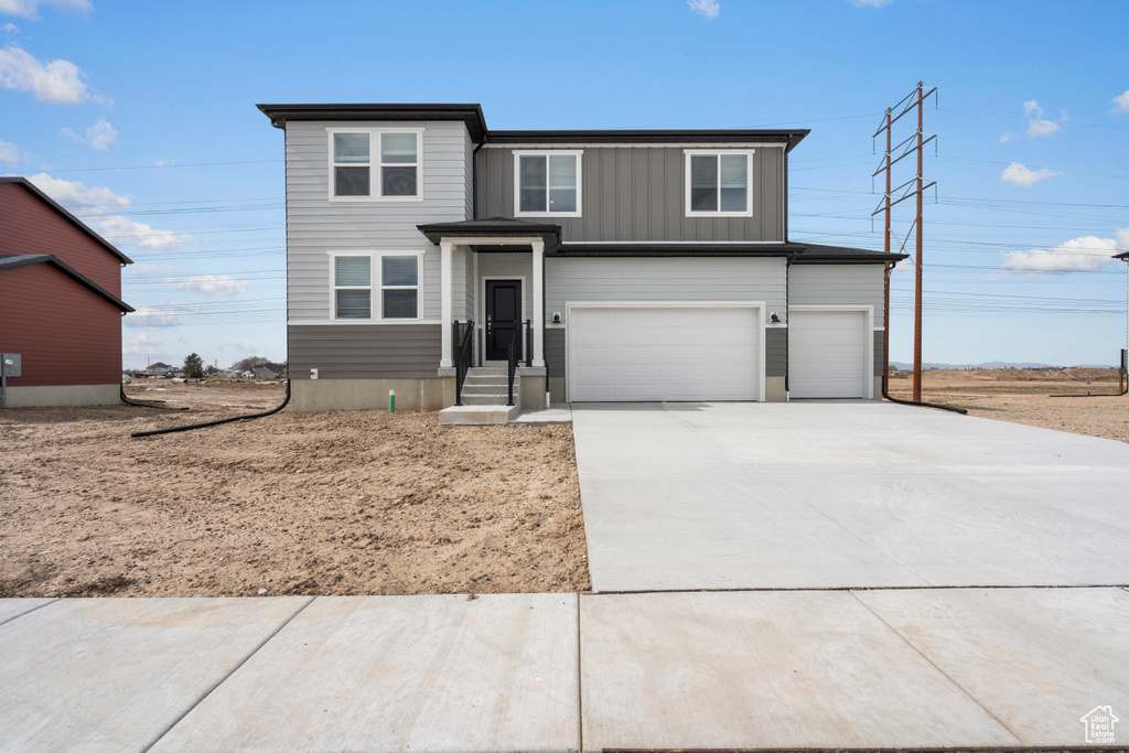 View of front of home with a garage, board and batten siding, and concrete driveway