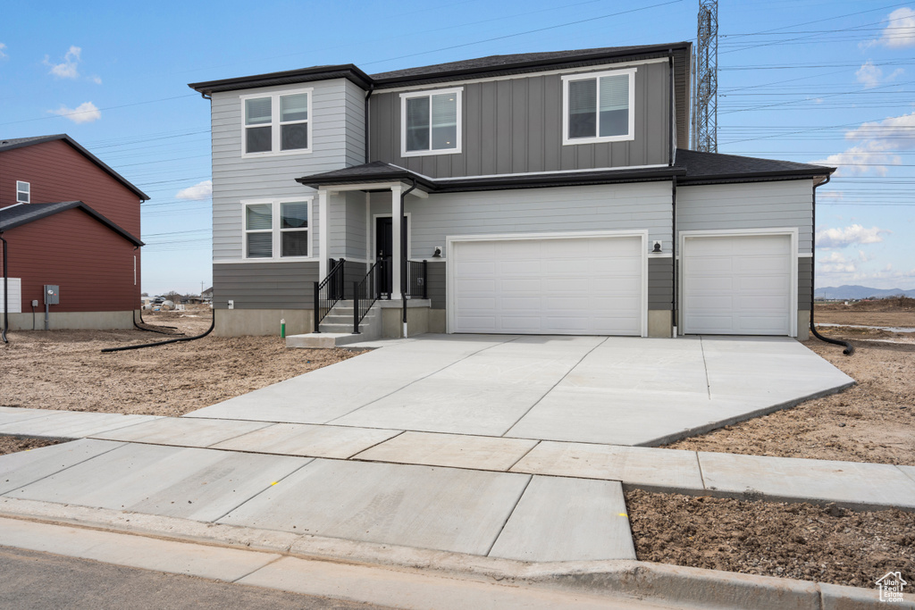 View of front of home with driveway, an attached garage, and board and batten siding