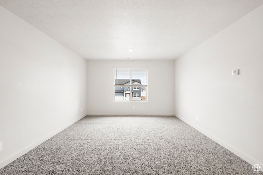 Empty room featuring light carpet and baseboards