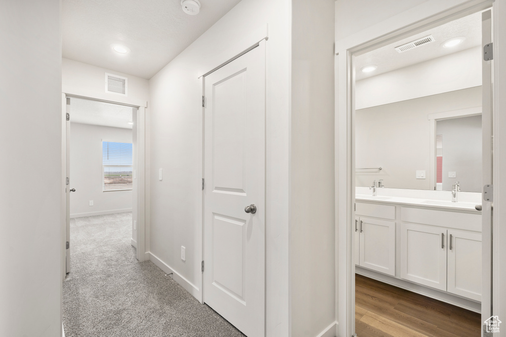 Corridor with a sink, baseboards, and visible vents