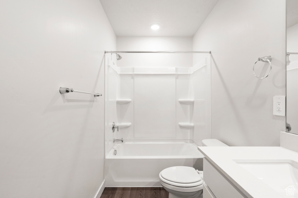 Bathroom with wood finished floors, toilet, vanity, and shower / washtub combination