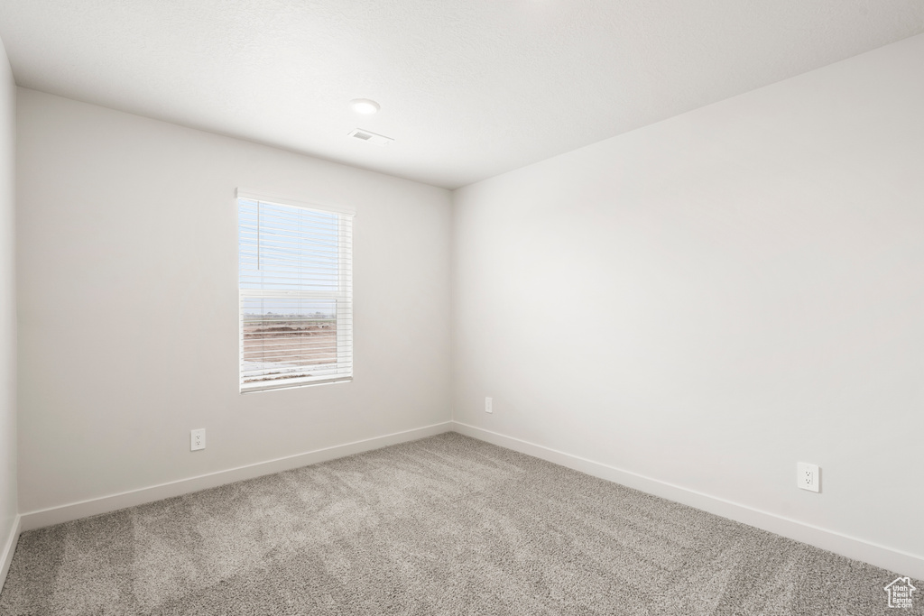 Empty room featuring baseboards, visible vents, and carpet