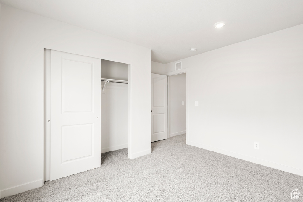 Unfurnished bedroom featuring a closet, baseboards, light colored carpet, and visible vents