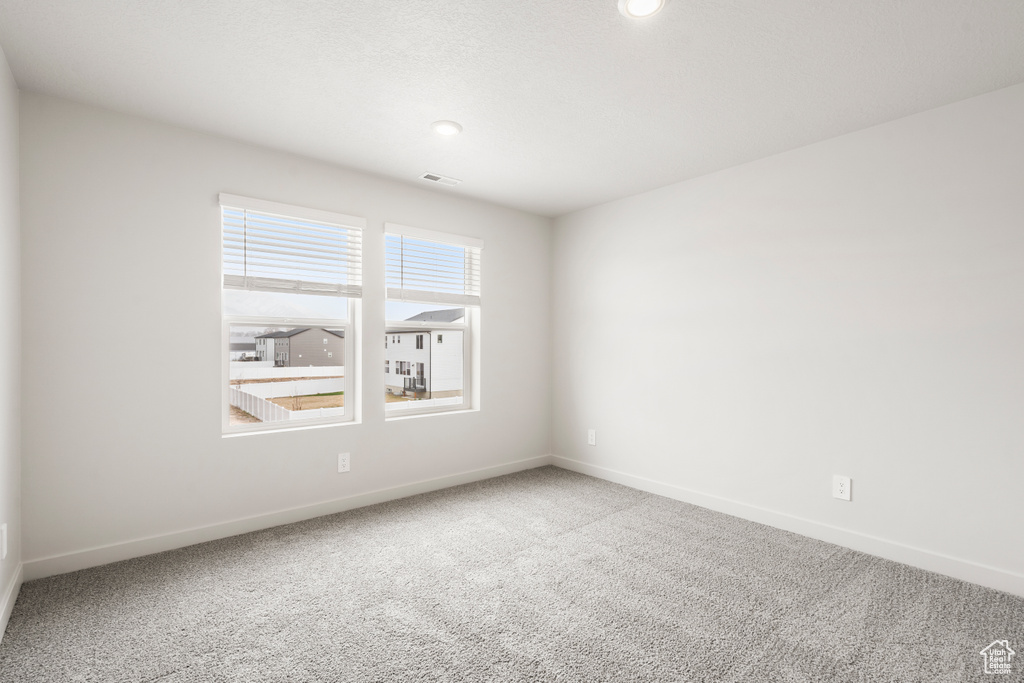 Carpeted spare room with baseboards and visible vents