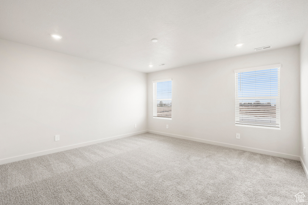 Spare room featuring light carpet, baseboards, visible vents, and recessed lighting