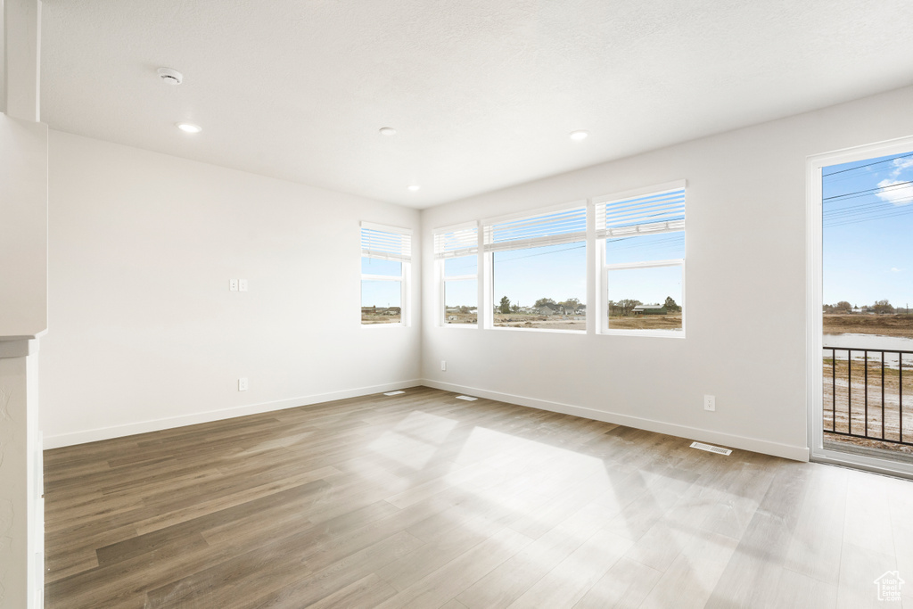 Spare room with baseboards, a wealth of natural light, and wood finished floors