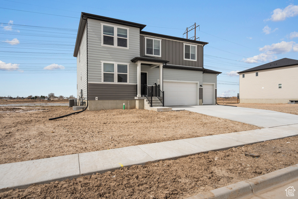 Traditional-style house with cooling unit, a garage, board and batten siding, and concrete driveway