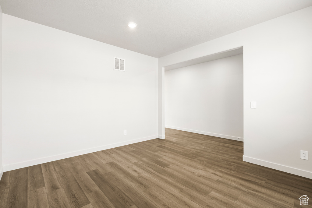 Empty room featuring recessed lighting, dark wood-style floors, baseboards, and visible vents