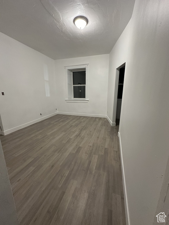 Spare room featuring dark wood-style flooring, a textured ceiling, and baseboards