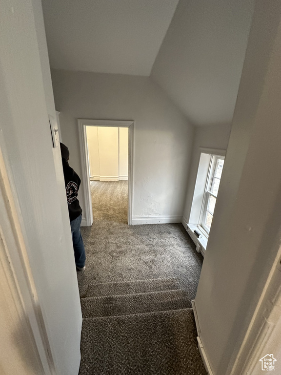 Interior space featuring carpet, vaulted ceiling, and baseboards