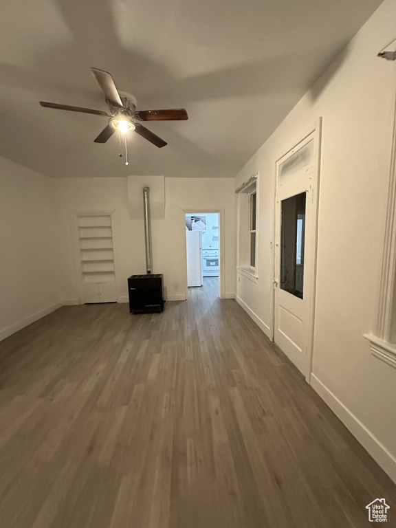 Unfurnished living room with dark wood-style flooring, ceiling fan, and baseboards