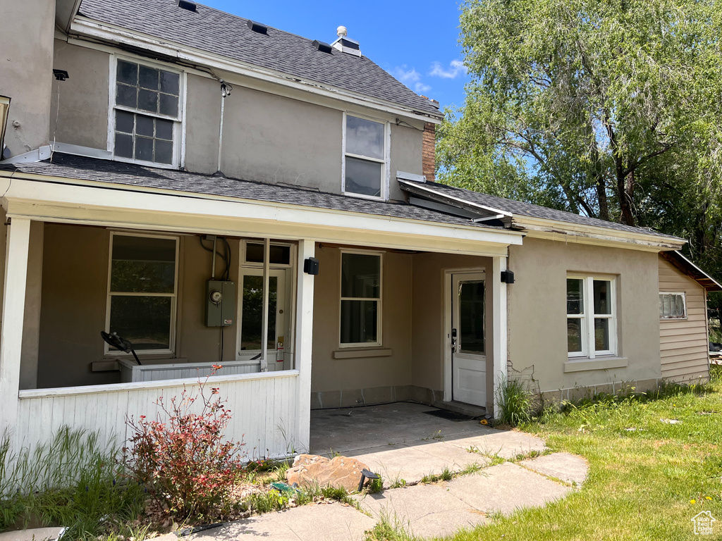 Back of house featuring a shingled roof and a porch