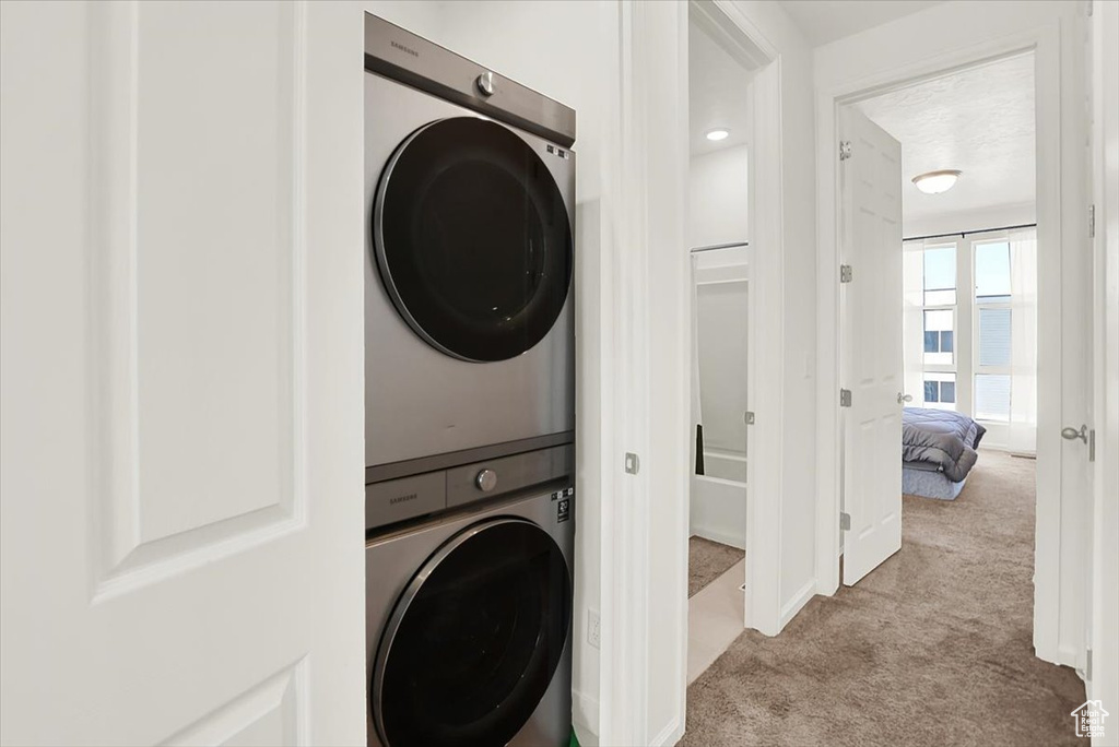 Clothes washing area with carpet floors and stacked washer / drying machine
