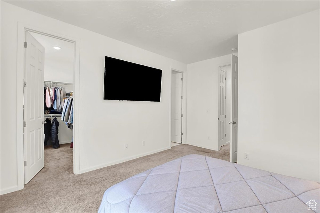 Carpeted bedroom with a walk in closet and a closet