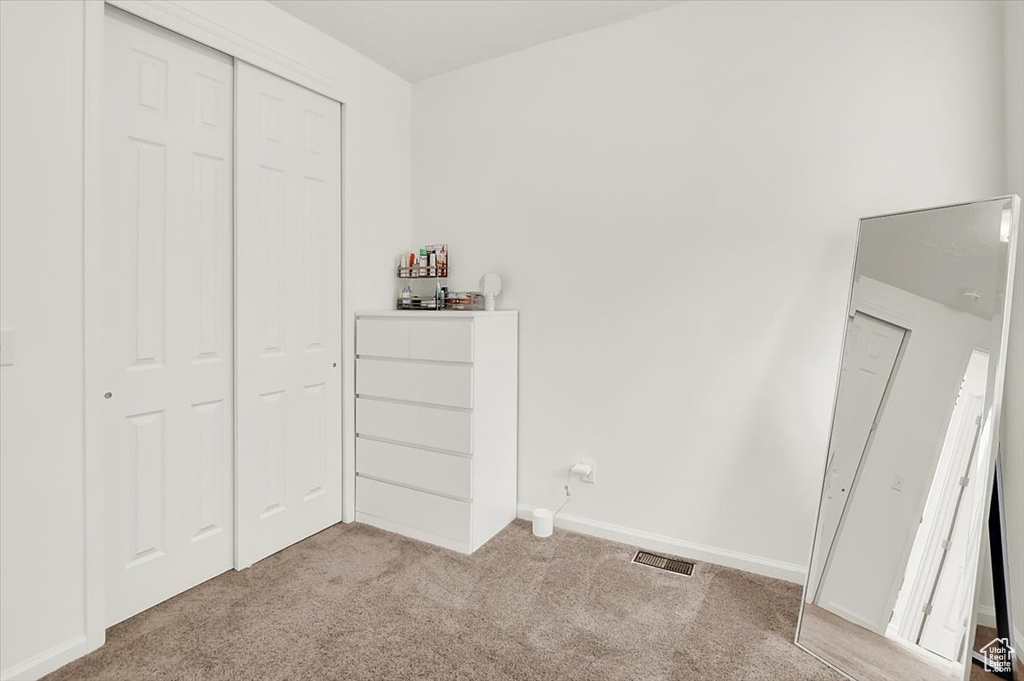 Unfurnished bedroom with carpet floors, a closet, visible vents, and baseboards