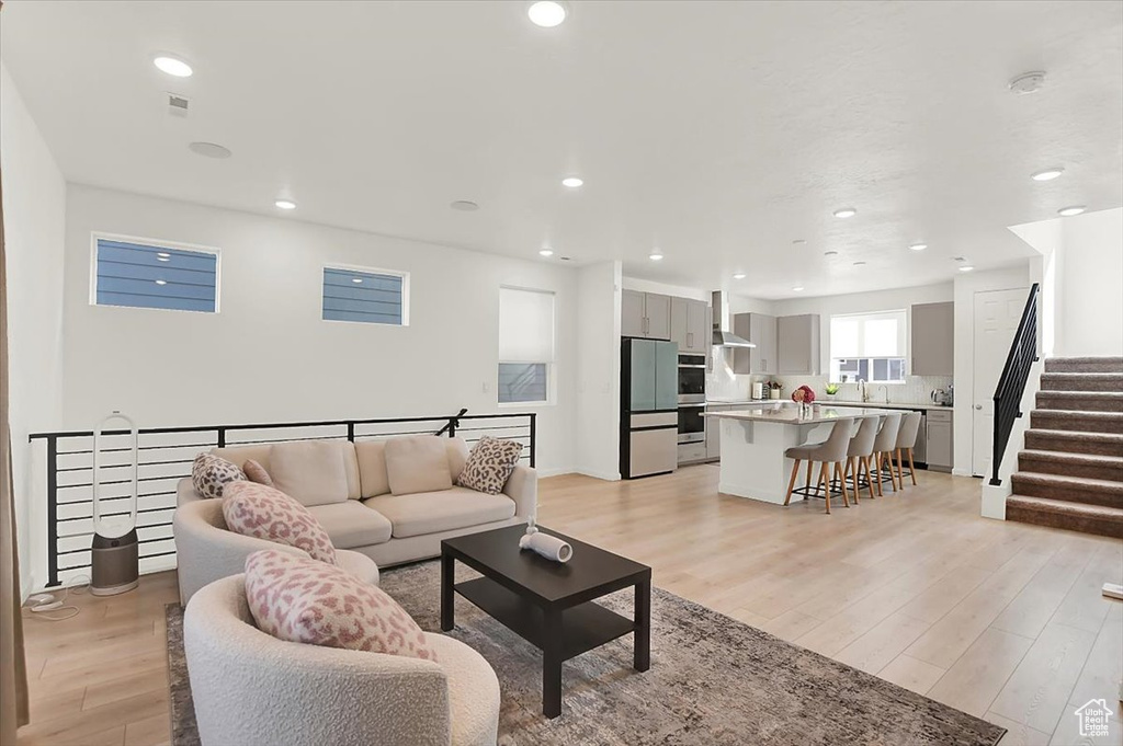 Living room featuring light wood-style floors, stairway, and recessed lighting