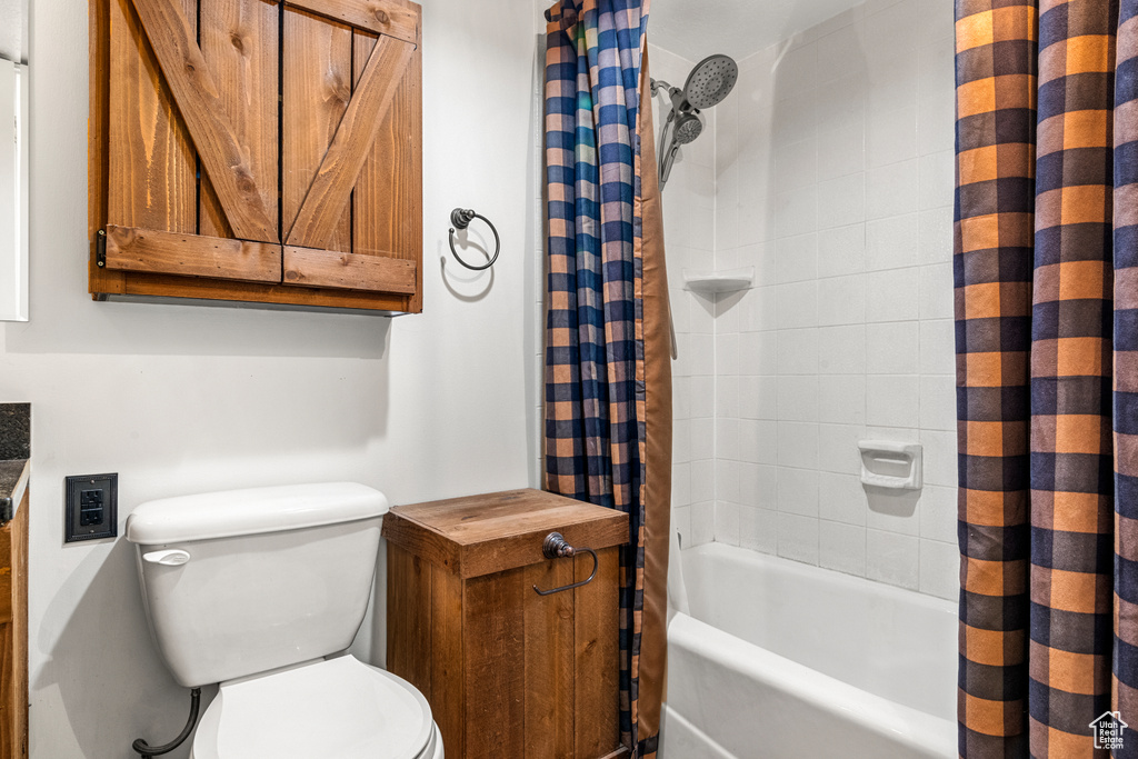 Bathroom featuring toilet and shower / bathtub combination with curtain
