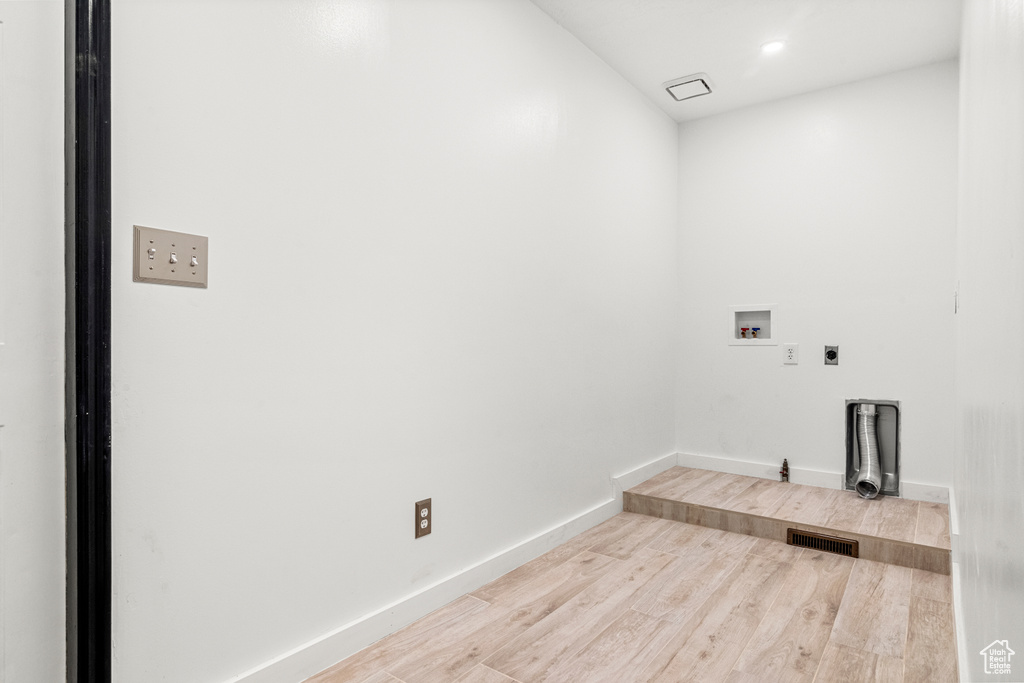 Washroom with hookup for a washing machine, laundry area, wood finished floors, visible vents, and baseboards