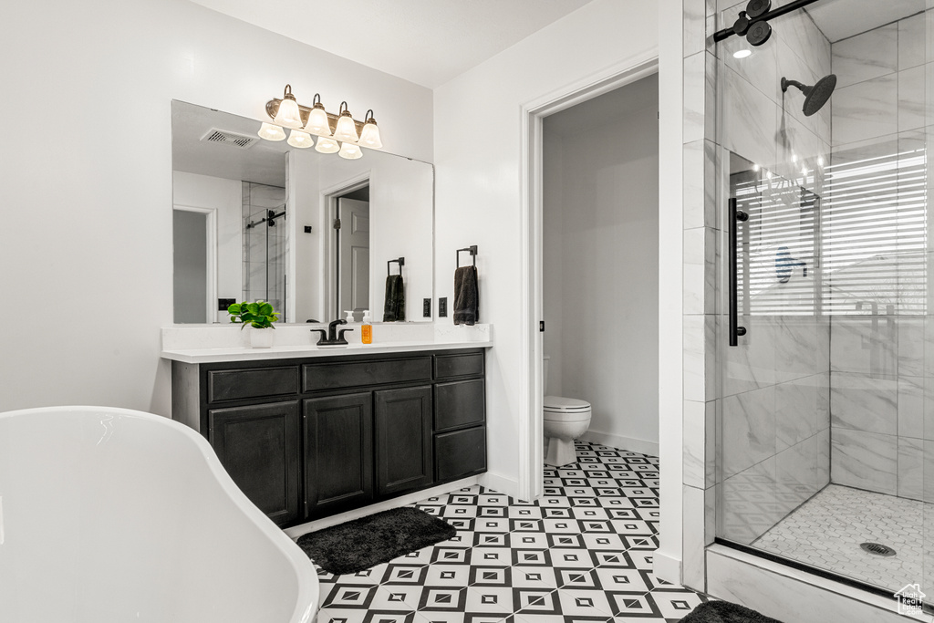 Full bath featuring toilet, vanity, visible vents, baseboards, and a stall shower