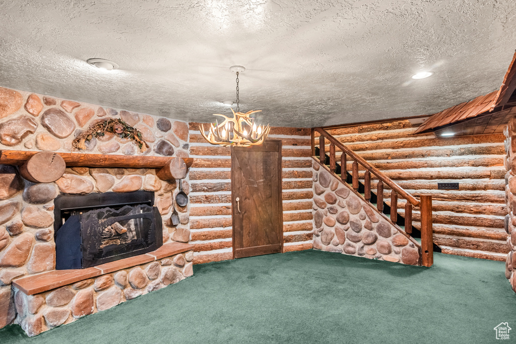 Unfurnished living room featuring stairway, carpet, a stone fireplace, and log walls