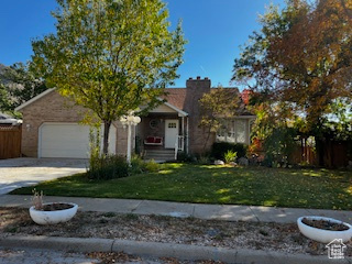 Obstructed view of property with an attached garage, concrete driveway, and a chimney