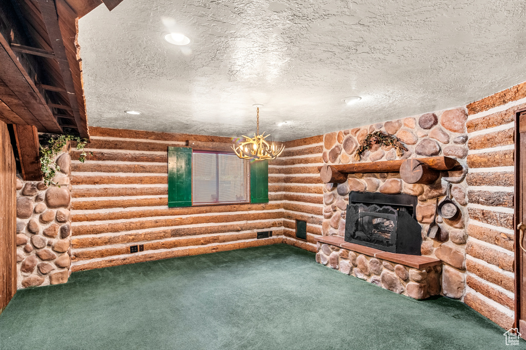 Unfurnished living room with carpet floors, rustic walls, a textured ceiling, and a stone fireplace