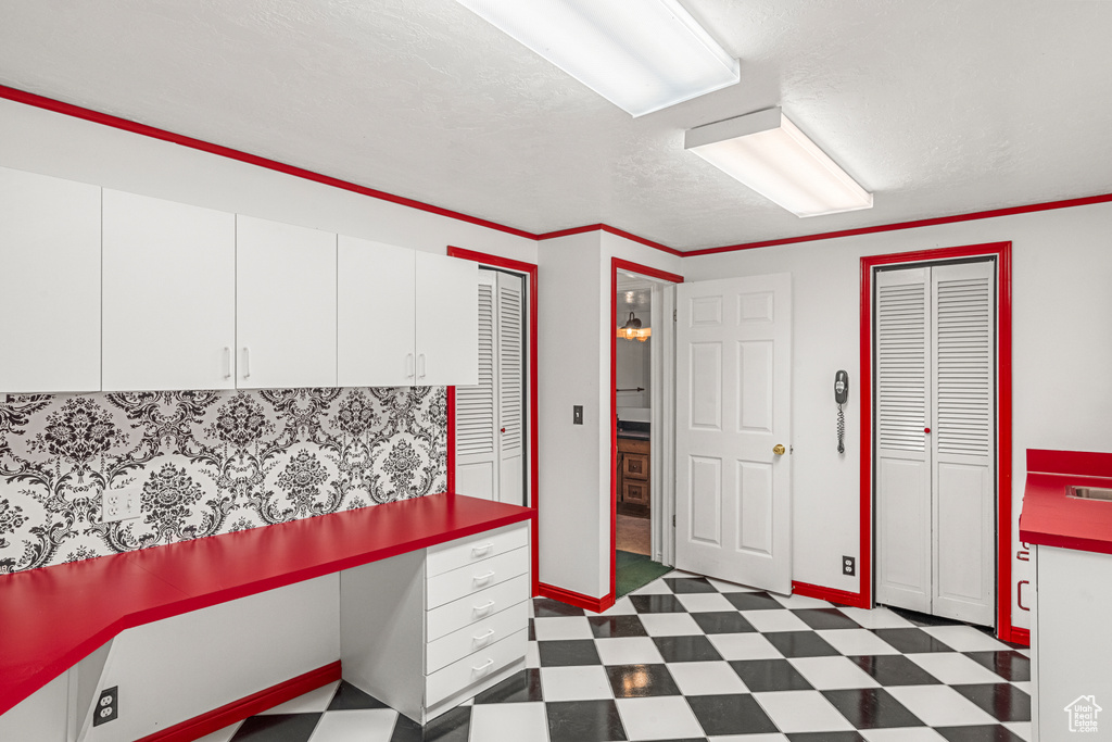 Kitchen with dark floors, white cabinets, a textured ceiling, and baseboards