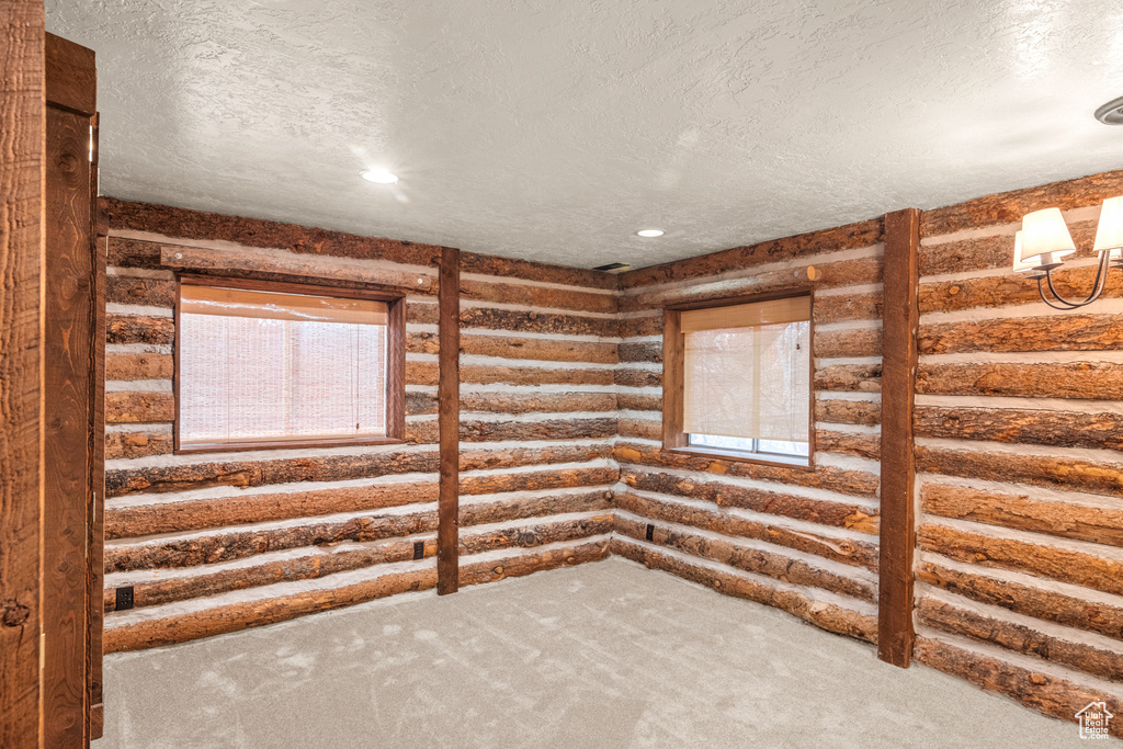 Unfurnished room featuring a textured ceiling, rustic walls, carpet flooring, and recessed lighting