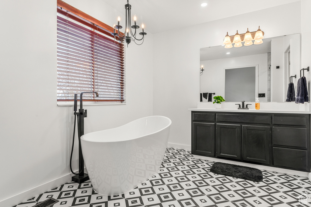 Bathroom featuring a freestanding bath, vanity, baseboards, and an inviting chandelier
