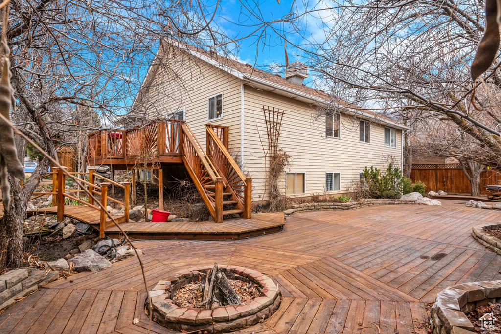 Back of house featuring a fire pit, a wooden deck, stairs, and fence