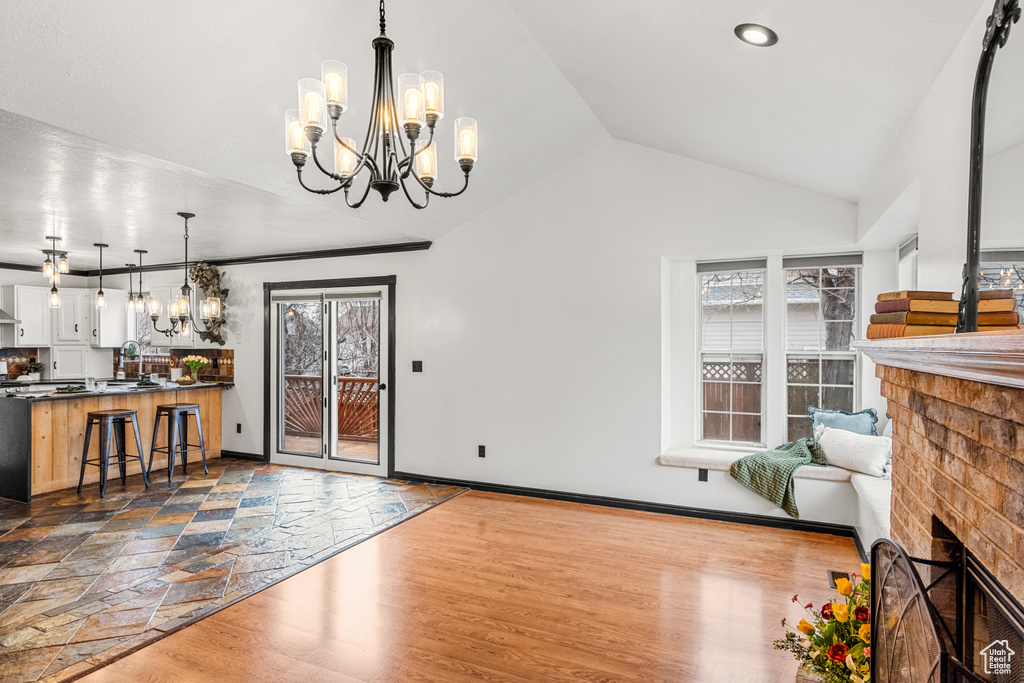Interior space with vaulted ceiling, a fireplace, dark wood finished floors, and a notable chandelier