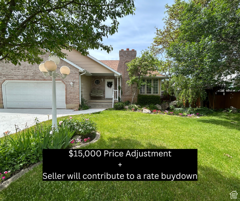 View of front of home with an attached garage, a chimney, driveway, brick siding, and a front lawn