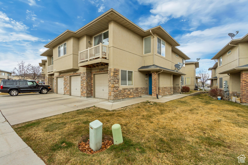 Townhome / multi-family property with a front yard, concrete driveway, an attached garage, and stucco siding
