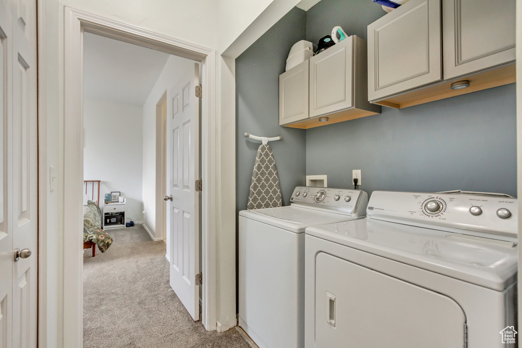 Laundry area with light carpet, cabinet space, baseboards, and washer and dryer