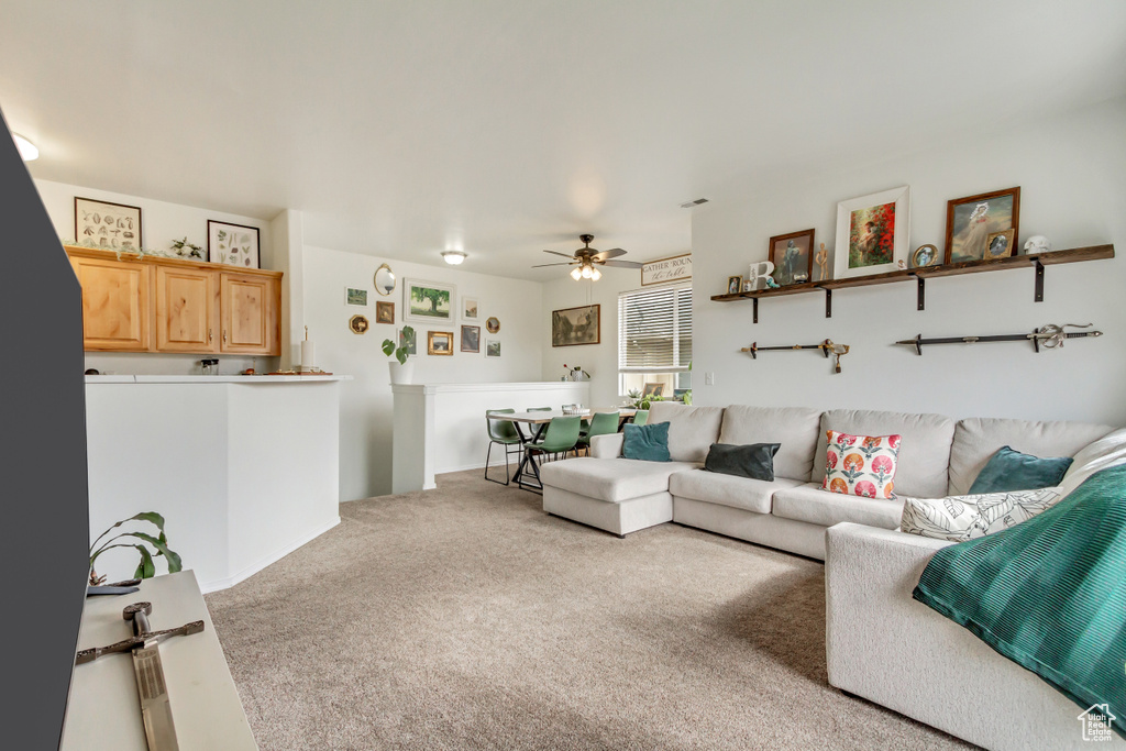 Carpeted living area featuring a ceiling fan