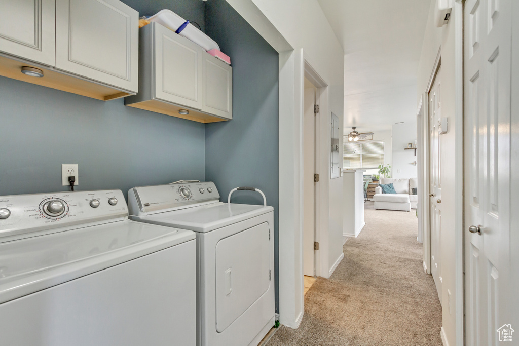 Clothes washing area with baseboards, washer and clothes dryer, cabinet space, and light colored carpet